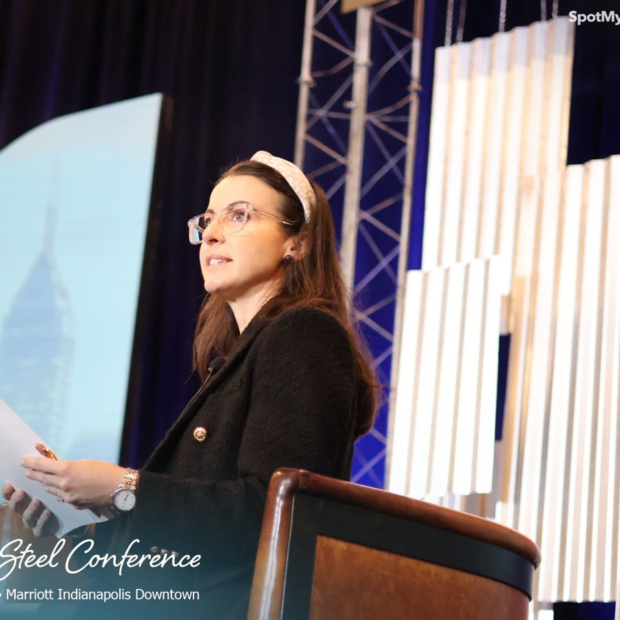 Betts seated on stage, listening during a session at the AIST Women in Steel Conference